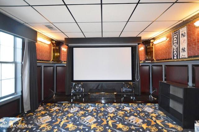 carpeted cinema room featuring a drop ceiling