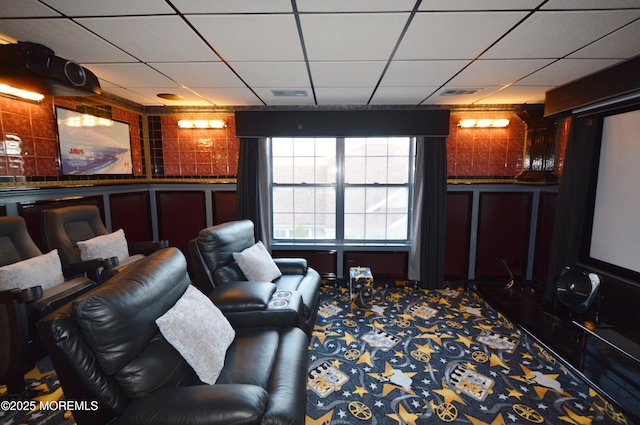 carpeted cinema room with a paneled ceiling