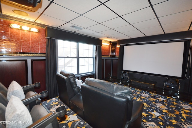 carpeted home theater featuring a drop ceiling