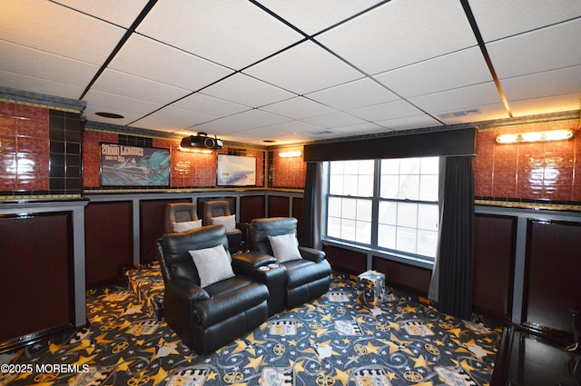 carpeted home theater featuring a drop ceiling