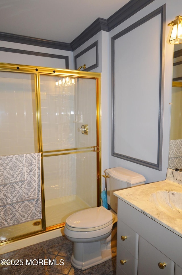 bathroom featuring toilet, vanity, crown molding, and a shower with shower door