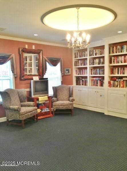 living area featuring built in features, an inviting chandelier, and ornamental molding