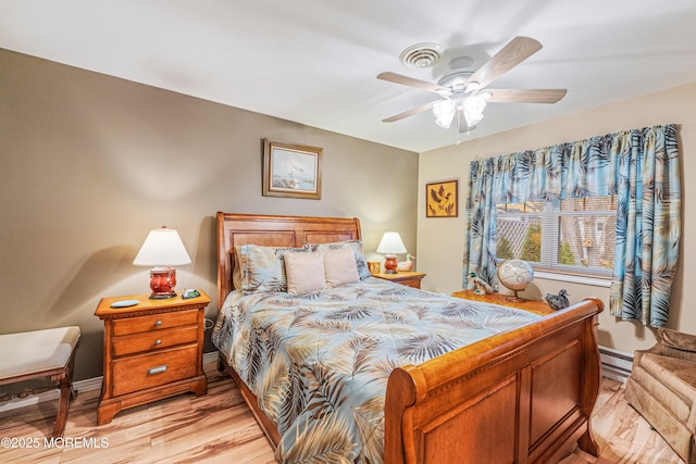 bedroom featuring ceiling fan, light hardwood / wood-style flooring, and a baseboard radiator