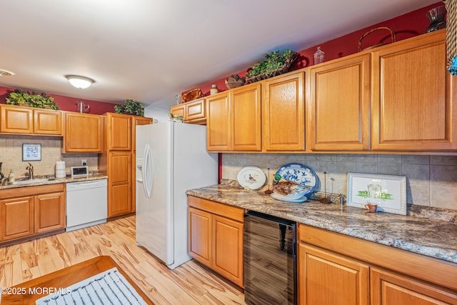 kitchen featuring light stone counters, white appliances, sink, and beverage cooler