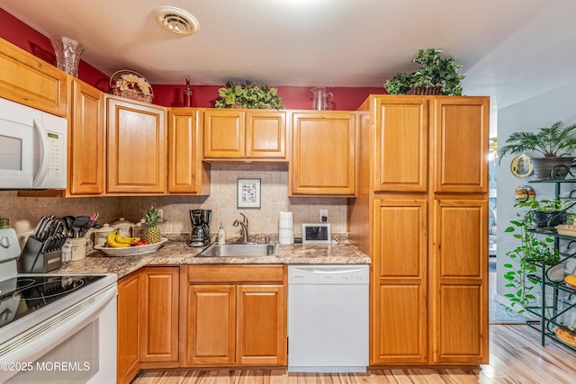 kitchen with white appliances, sink, light hardwood / wood-style flooring, tasteful backsplash, and light stone counters