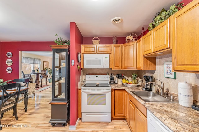 kitchen featuring backsplash, light wood-type flooring, white appliances, and sink