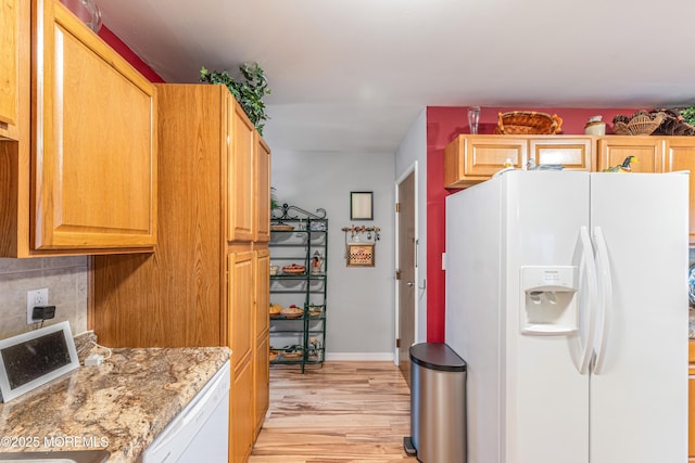 kitchen featuring decorative backsplash, light stone countertops, white appliances, and light wood-type flooring