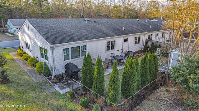 rear view of house featuring central AC and a lawn