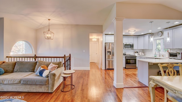 living room featuring sink, lofted ceiling, and light hardwood / wood-style flooring