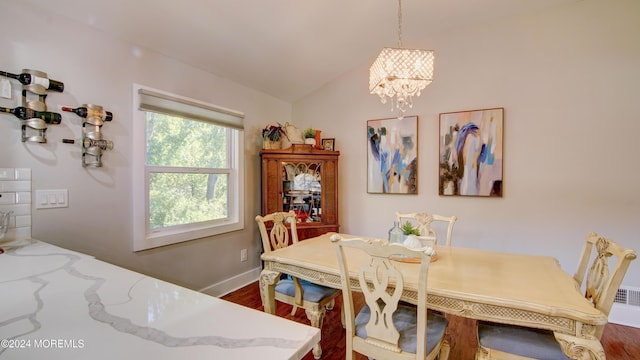 dining room featuring dark hardwood / wood-style floors, lofted ceiling, and an inviting chandelier