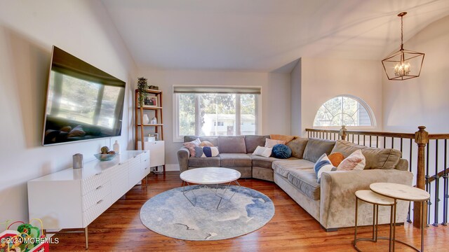 living room with hardwood / wood-style flooring, a wealth of natural light, lofted ceiling, and a notable chandelier