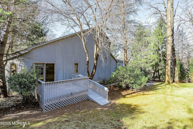 back of property with a wooden deck, a yard, and central AC