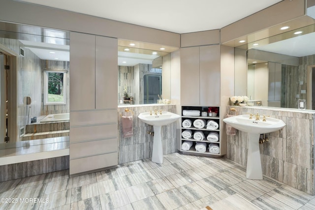 bathroom featuring sink, a tub to relax in, and tile walls