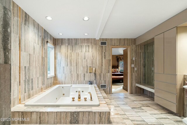 bathroom featuring beamed ceiling, tiled bath, and tile walls