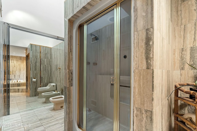 bathroom featuring toilet, tile walls, a bidet, and walk in shower