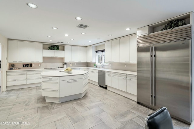 kitchen with a kitchen island, white cabinets, and appliances with stainless steel finishes