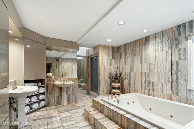 bathroom with a relaxing tiled tub, tile walls, and toilet