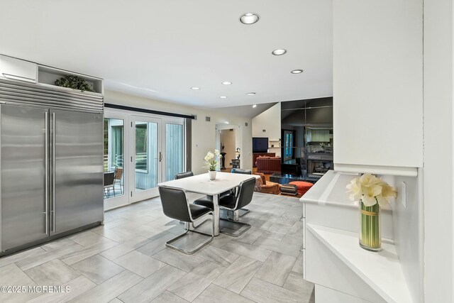 interior space with a fireplace, stainless steel built in fridge, and vaulted ceiling