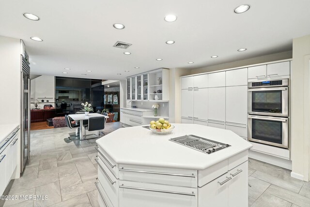 kitchen with double oven, white cabinetry, and a center island