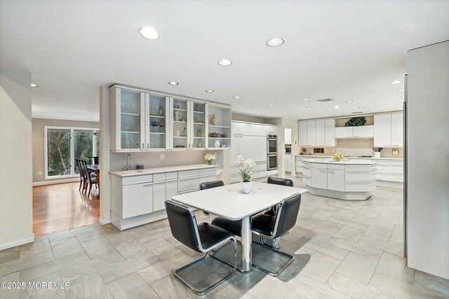 kitchen with white cabinetry, a kitchen island, double oven, and sink