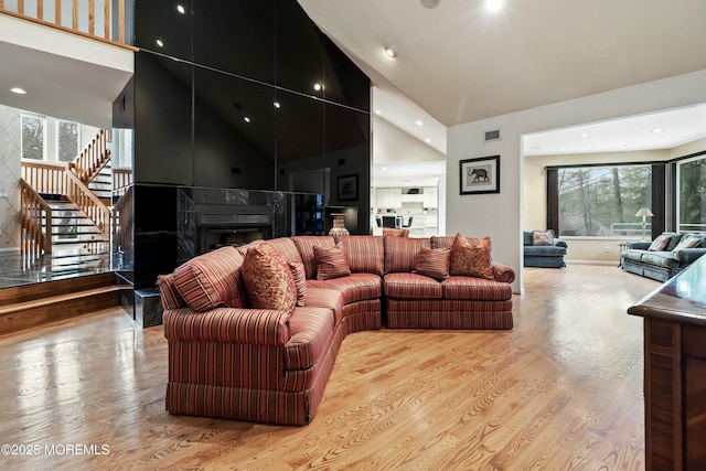 living room with a fireplace, light hardwood / wood-style floors, and a high ceiling