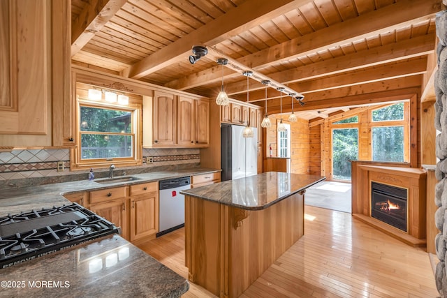 kitchen with pendant lighting, backsplash, dark stone counters, appliances with stainless steel finishes, and a kitchen island