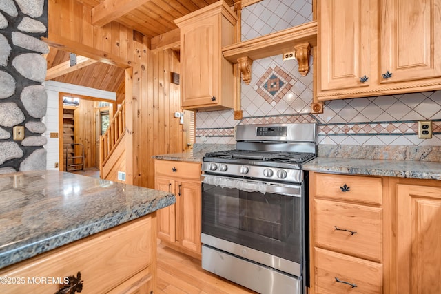 kitchen with light brown cabinets, stainless steel gas range oven, beamed ceiling, dark stone countertops, and wood ceiling