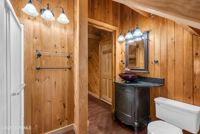 bathroom with wood-type flooring, vanity, toilet, and wooden walls