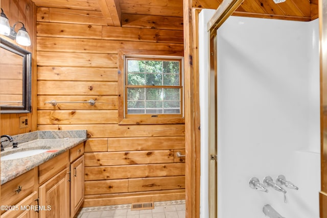 bathroom with wooden walls, shower / washtub combination, vanity, and beamed ceiling