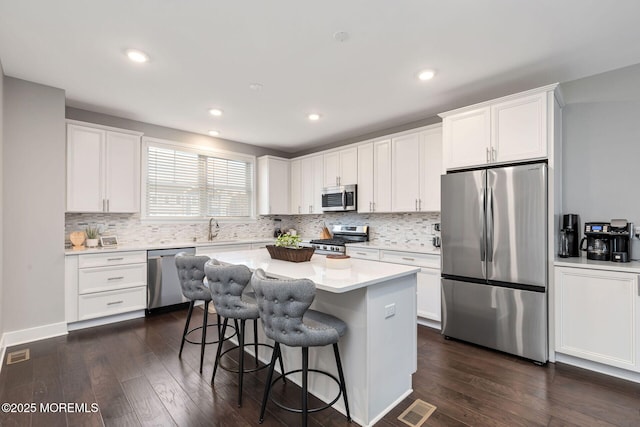 kitchen featuring dark wood-style floors, a breakfast bar, visible vents, appliances with stainless steel finishes, and a sink