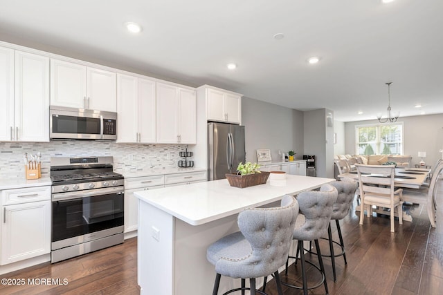 kitchen featuring stainless steel appliances, a center island, dark wood-style flooring, and backsplash