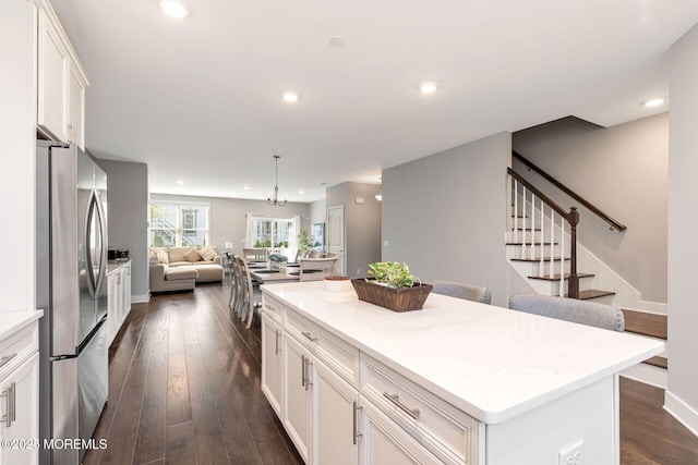 kitchen featuring white cabinets, a kitchen island, dark wood-type flooring, freestanding refrigerator, and recessed lighting