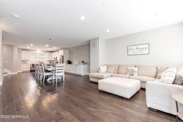 living area featuring dark wood-style flooring, a notable chandelier, recessed lighting, visible vents, and baseboards