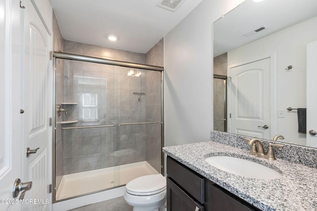 bathroom with toilet, a stall shower, and visible vents