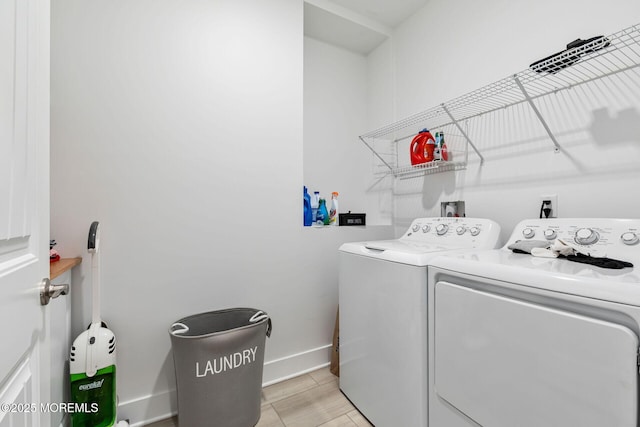 clothes washing area with laundry area, baseboards, and separate washer and dryer