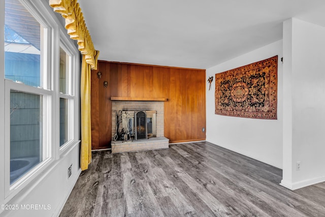 unfurnished living room featuring wooden walls, a fireplace, and wood-type flooring