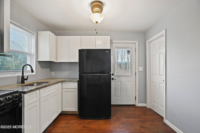 kitchen featuring dark stone counters, a healthy amount of sunlight, sink, black appliances, and white cabinets