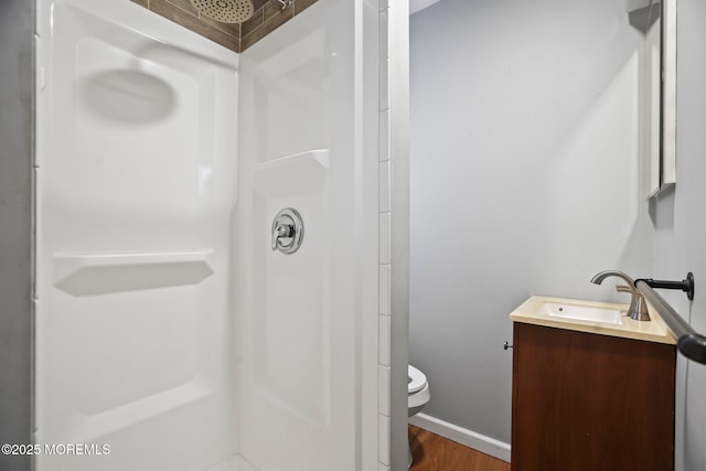 bathroom with a shower, hardwood / wood-style floors, vanity, and toilet