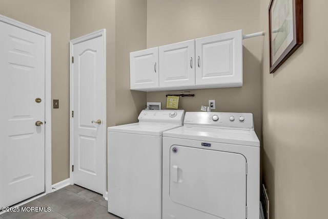 laundry area with cabinets, light tile patterned floors, and washing machine and clothes dryer