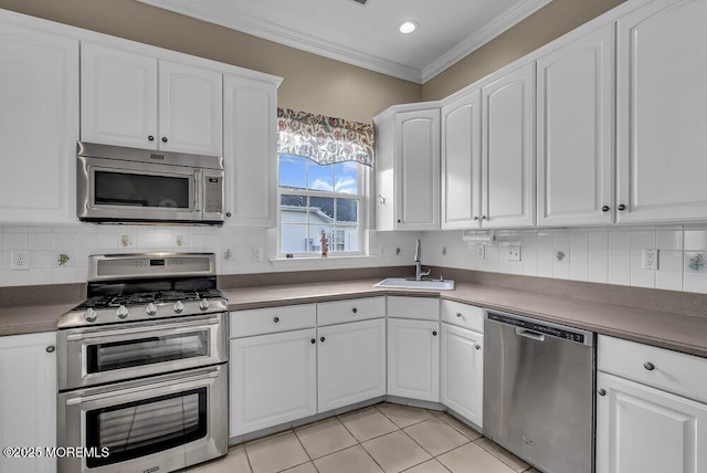 kitchen featuring white cabinetry, sink, stainless steel appliances, crown molding, and light tile patterned floors