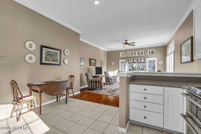 kitchen with range, crown molding, ceiling fan, light tile patterned floors, and white cabinetry