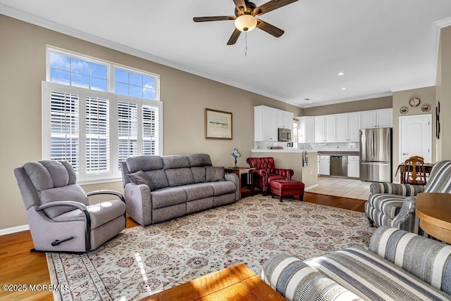 living room with ceiling fan, crown molding, and light hardwood / wood-style flooring