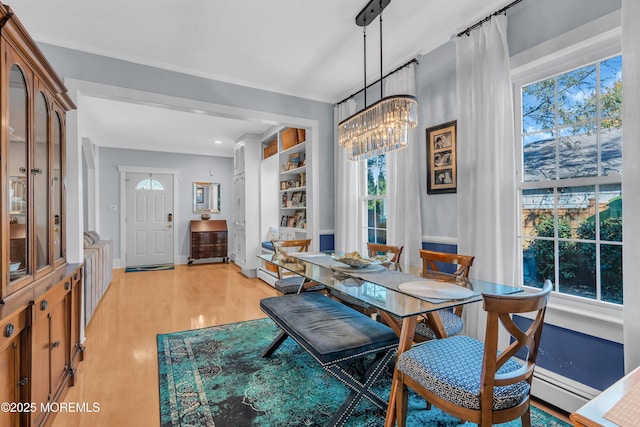 dining room featuring light hardwood / wood-style floors, built in features, and an inviting chandelier