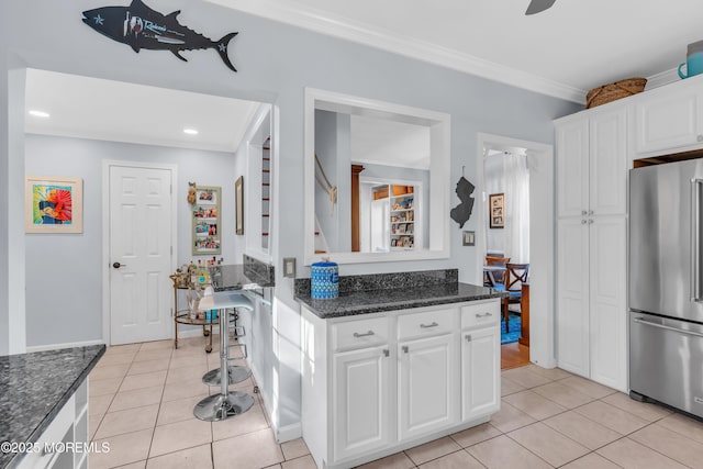 kitchen with white cabinetry, high end fridge, ornamental molding, and light tile patterned floors