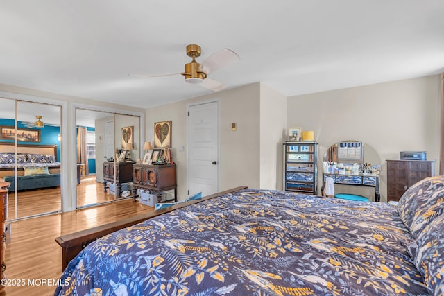 bedroom with hardwood / wood-style flooring, two closets, and ceiling fan