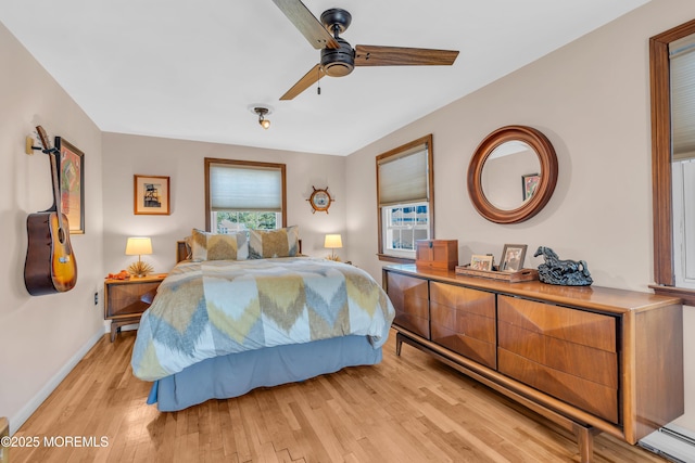 bedroom featuring ceiling fan, baseboard heating, and light hardwood / wood-style flooring