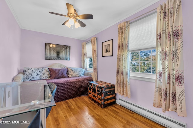 sitting room with ceiling fan, hardwood / wood-style flooring, a baseboard heating unit, and ornamental molding