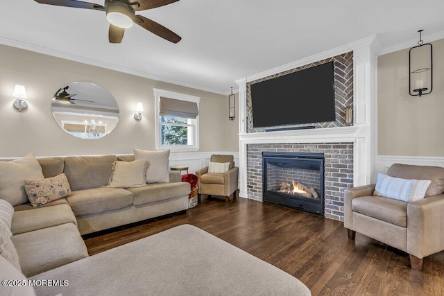 living room featuring dark hardwood / wood-style floors, a brick fireplace, ceiling fan, and ornamental molding