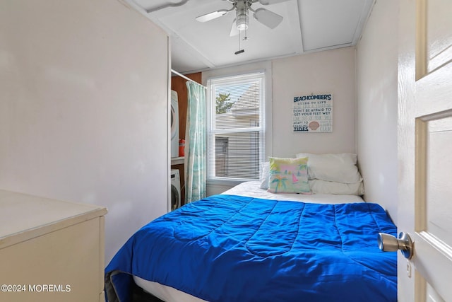 bedroom with ceiling fan and stacked washer / dryer