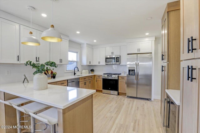 kitchen with hanging light fixtures, stainless steel appliances, tasteful backsplash, kitchen peninsula, and white cabinets